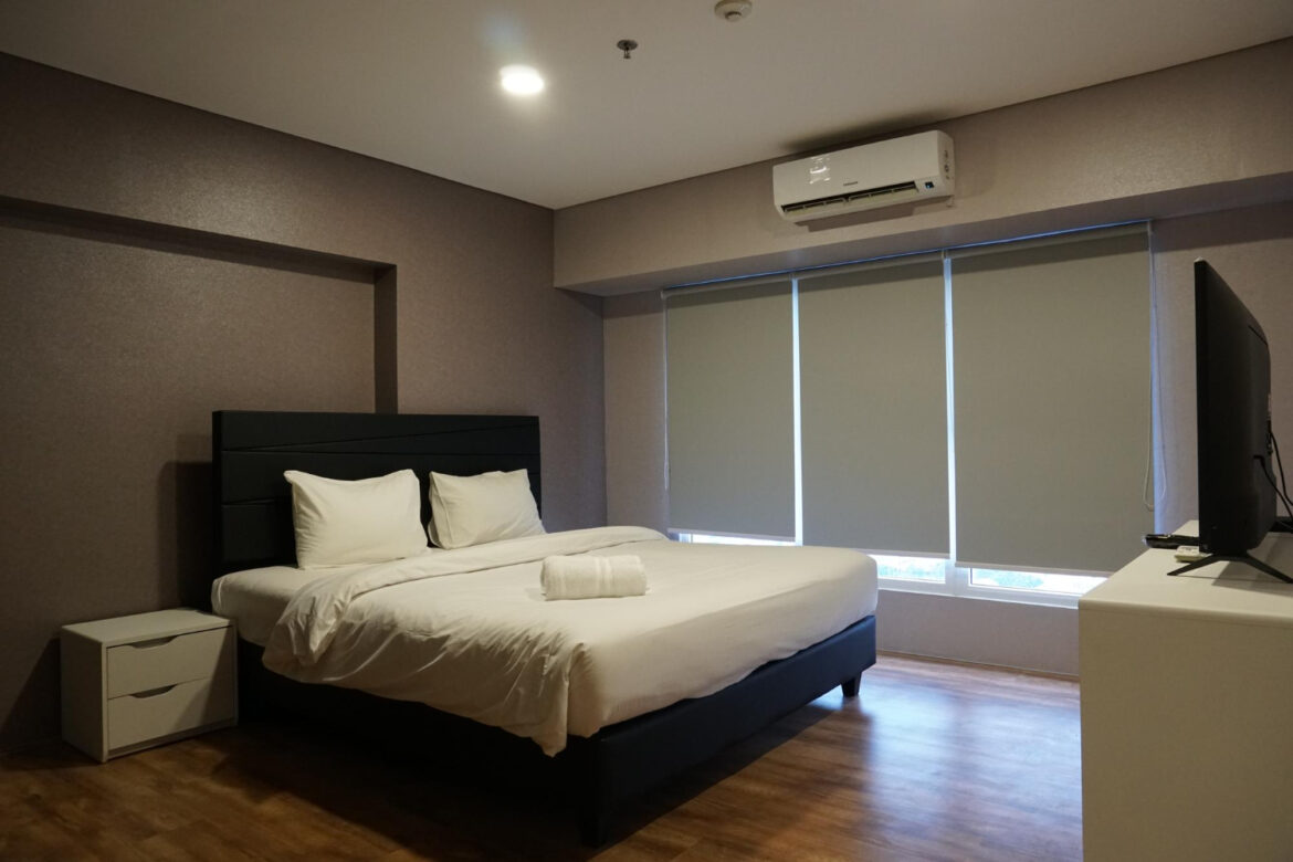 A bedroom with windows covered by electric blackout blinds.